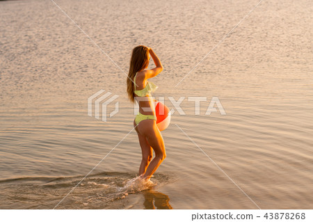 slim lady in swimsuit with beach ball in the sea 43878268