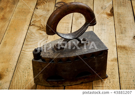 vintage old rusty iron on a bright wooden table vintage old rusty iron on a bright wooden table 43881207