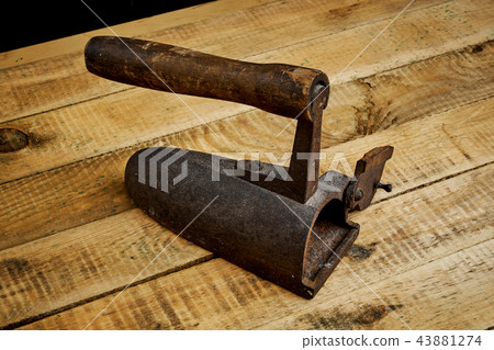 vintage old rusty iron on a bright wooden table vintage old rusty iron on a bright wooden table 43881274