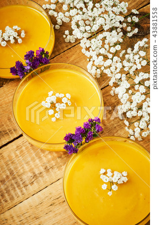 delicious pumpkin soup and flowers on an old wooden kitchen table 43881558