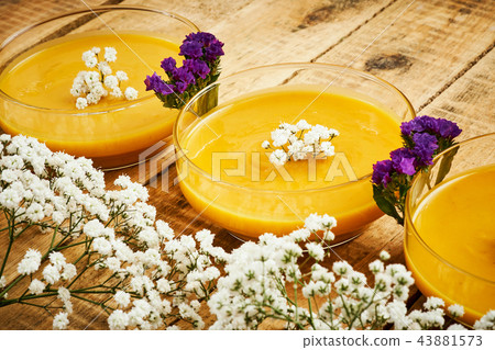 delicious pumpkin soup and flowers on an old wooden kitchen table 43881573
