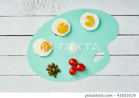 three delicious fried egg tomatoes and basil leaves on chopping board 43881629