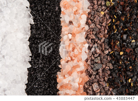 Various coarse grain salts on black stone background. 43883447