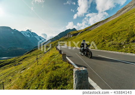 Motorcycle driver riding in Alpine highway on famous Hochalpenstrasse, Austria, Europe. 43884143