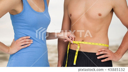 Couple measuring weight with measuring tape on waist on Summer beach Couple measuring weight with measuring tape on waist on Summer beach 43885132