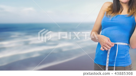 Woman measuring weight with measuring tape on waist on Summer beach 43885308