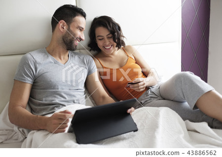 Happy Young Couple In Bed Buying Travel On Line 43886562
