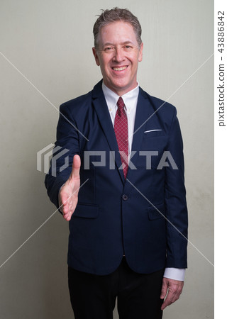 Portrait of mature businessman against white background 43886842