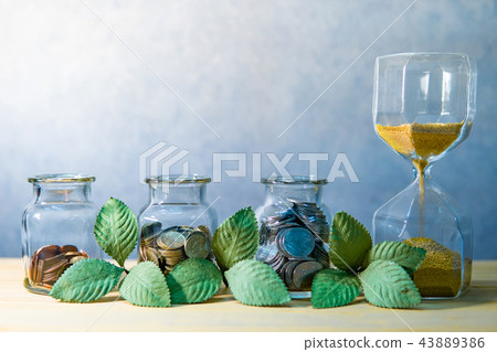 Coin jars with plant and hourglass. Saving money Coin jars with plant and hourglass. Saving money 43889386