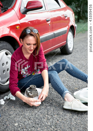 young girl sitting on the road by the red car young girl sitting on the road by the red car 43899456