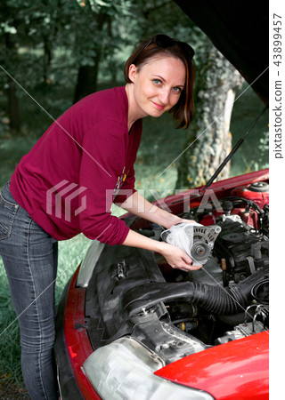 young girl sitting on the road by the red car  43899457