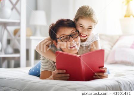 Grandmother reading a book to granddaughter Grandmother reading a book to granddaughter 43901481