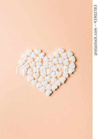 Heart shaped pills on a beige background. 43902563