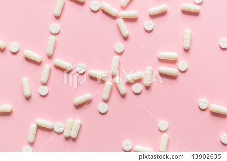 Pink background with white tablets and pills. Pink background with white tablets and pills. 43902635