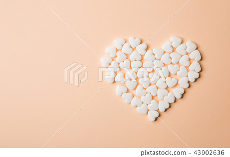 Heart shaped pills on a beige background. Heart shaped pills on a beige background. 43902636