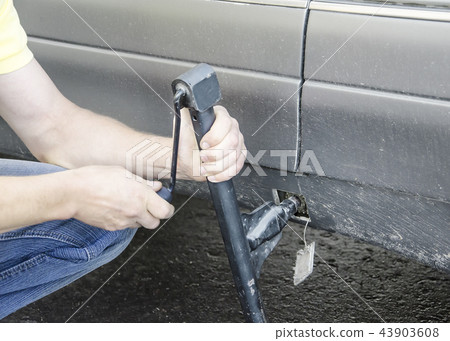 man puts a car jack for changing the wheel man puts a car jack for changing the wheel 43903608
