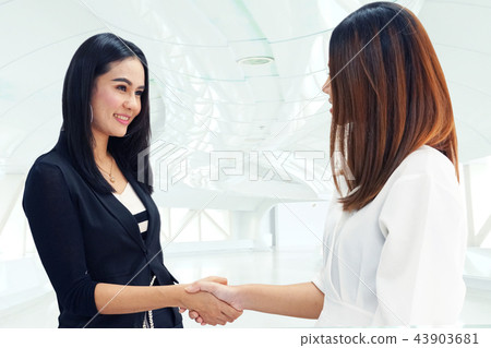 Two working women shaking hands  43903681