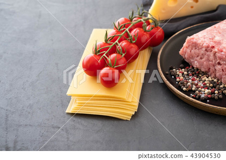 Ingredients for Italian lasagna with fresh cherry tomatoes and green basil leaves on sheets of dried Ingredients for Italian lasagna with fresh cherry tomatoes and green basil leaves on sheets of dried 43904530