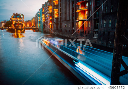 A colorfully illuminated boat cruising on the Wandrahmsfleet at night. The Warehouse District in 43905352