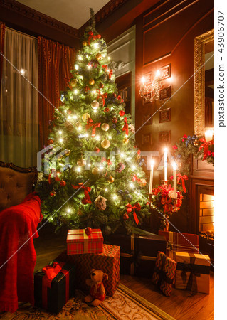 gifts at the Christmas tree. Christmas evening by candlelight. classic apartments with a fireplace. gifts at the Christmas tree. Christmas evening by candlelight. classic apartments with a fireplace. 43906707