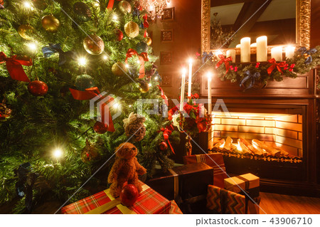 gifts at the Christmas tree. Christmas evening by candlelight. classic apartments with a fireplace. 43906710
