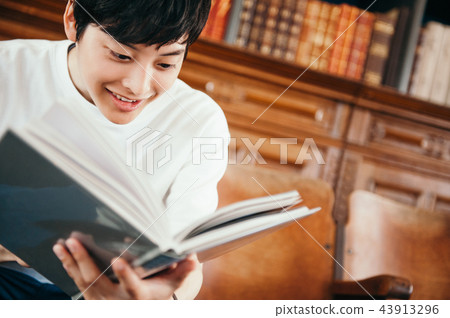 A man reading a book in a library 43913296