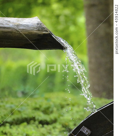 water flows from a wooden pipe or water gushing  43914822