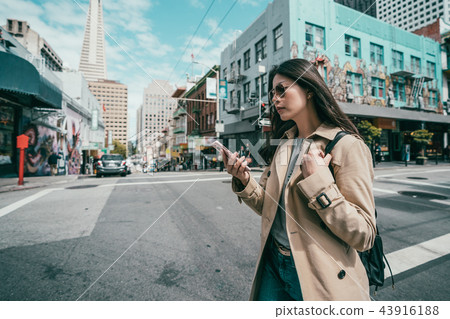 woman using cell phone while crossing the road woman using cell phone while crossing the road 43916188