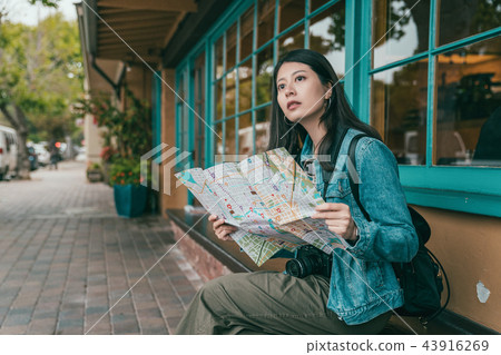 woman sitting and checking with a guide map woman sitting and checking with a guide map 43916269