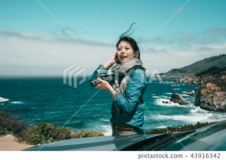 woman taking photos of spectacular ocean 43916342