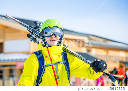 Image of sportive man in helmet with skis on his shoulder against building background Image of sportive man in helmet with skis on his shoulder against building background 43919813