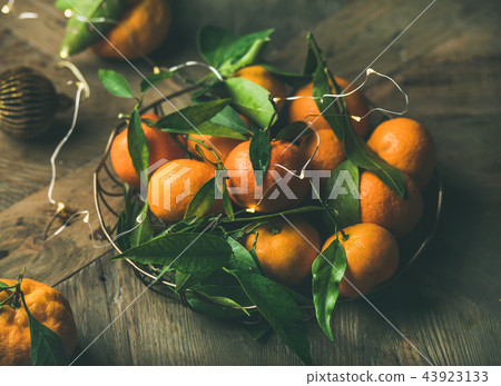 Fresh tangerines with leaves and decoration toys on holiday table Fresh tangerines with leaves and decoration toys on holiday table 43923133
