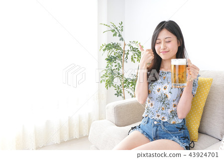 Young woman drinking beer at home 43924701