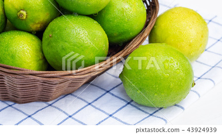 Green lime in a basket on a white wooden table. Green lime in a basket on a white wooden table. 43924939