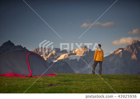 Hiker in a camp and looking at mountains in a sumer day. 43925936