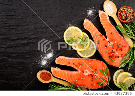 Slice of red fish salmon with lemon, rosemary on black stone background with copy space for your 43927396