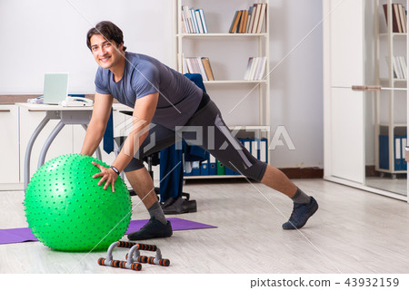 Young male employee exercising in the office Young male employee exercising in the office 43932159