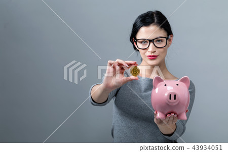 Young woman with bitcoin and a piggy bank Young woman with bitcoin and a piggy bank 43934051
