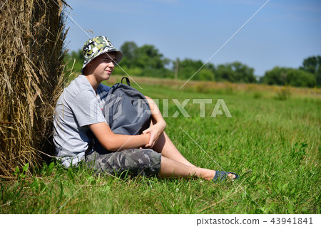 teenager with backpack sitting next to stack of straw teenager with backpack sitting next to stack of straw 43941841