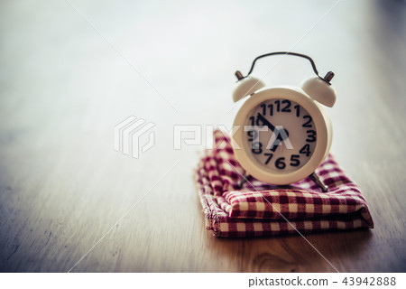 White alarm clock and handkerchief on white table 43942888