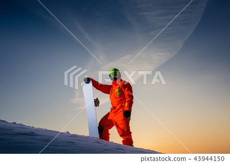 Snowboarder on the top of the ski slope at the background of beautiful sunset 43944150