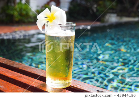 a glass of beer with plumeria flower on wooden 43944186