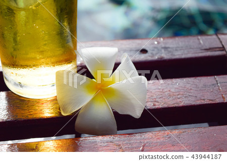 a glass of beer with plumeria flower on wooden  43944187