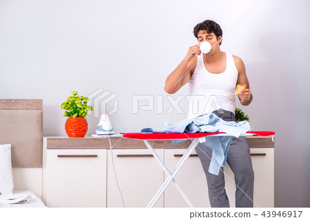 Young man ironing in the bedroom  43946917