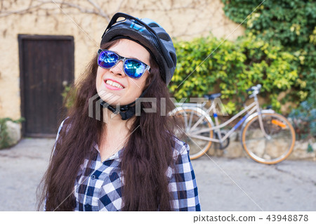 Happy woman with helmet and sunglasses posing backgound bicycle and street 43948878