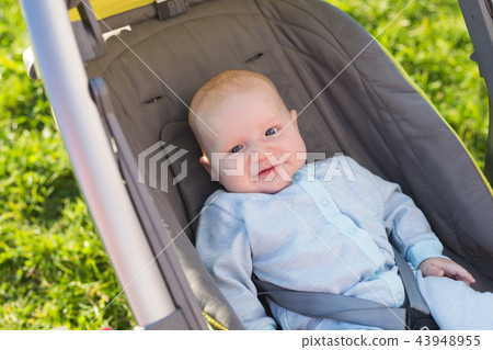 Adorable baby boy sitting in the pram and smiling Adorable baby boy sitting in the pram and smiling 43948955