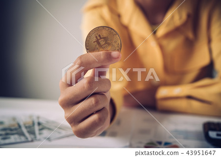 Hand of a businessman holding a gold bitcoin Hand of a businessman holding a gold bitcoin 43951647