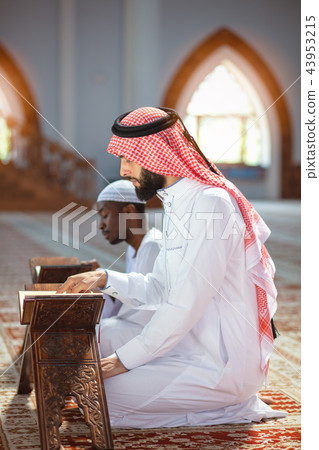 Muslim men praying with holy books in mosque Muslim men praying with holy books in mosque 43953215