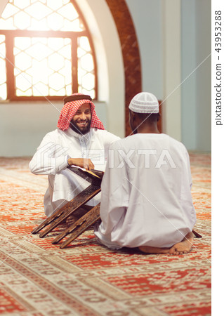 Muslim men praying with holy books in mosque Muslim men praying with holy books in mosque 43953288