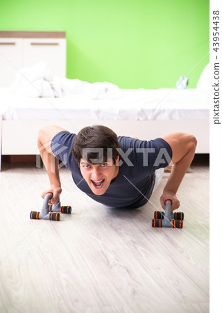 Young man in pajamas doing morning exercises Young man in pajamas doing morning exercises 43954438